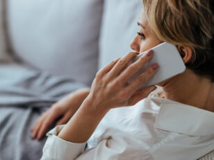 Pensive woman talking on the phone while relaxing on the sofa at